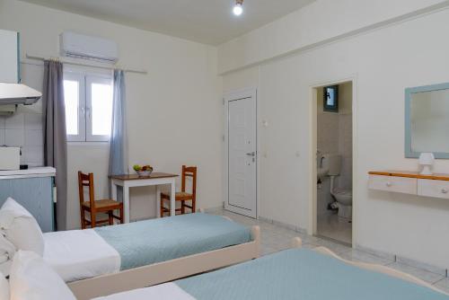 um quarto com 2 camas, uma mesa e uma casa de banho em Giant Woman em Tsoutsouros