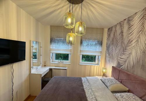 a bedroom with a bed and a television and windows at Violet deluxe in Niš