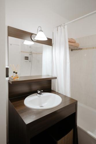 une salle de bain avec un lavabo et un miroir dans l'établissement NeuvaRoom, à Montévrain