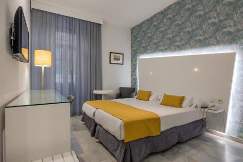 マラガにあるアタラサナス マラガ ブティック ホテルのベッドとガラスのテーブルが備わるホテルルームです。
