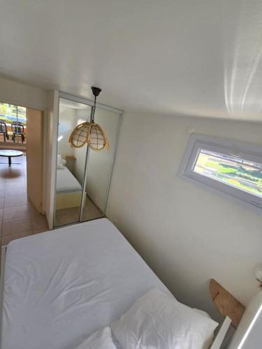 une chambre avec un lit blanc et une fenêtre dans l'établissement Cap d'Agde proche port et plage, au Cap d'Agde