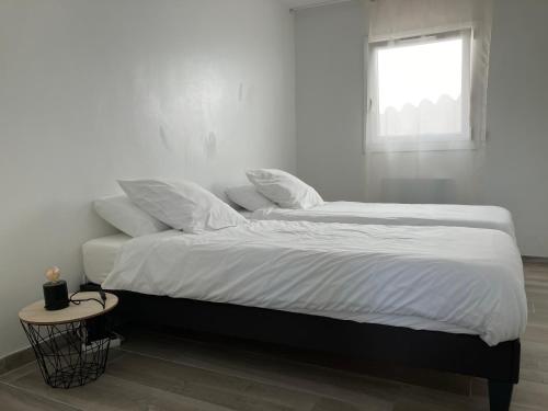 un lit avec des draps blancs et des oreillers dans une chambre dans l'établissement Maison de L'Étang de Berre, à Saint-Mitre-les-Remparts