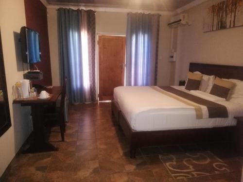 PalapyeにあるThe Tamek Palace Hotelのベッドと机とテレビのある寝室