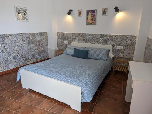 a bedroom with a white bed with blue sheets at Casa Celeste Trabuco in Villanueva del Trabuco