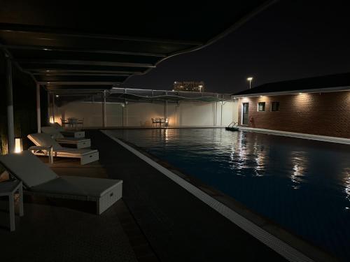 a swimming pool at night with chairs and a swimming pooliterator at Tamimi Geshla Residency in Al Khobar