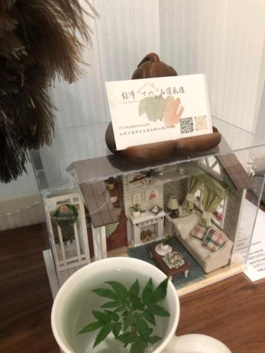 una estantería de cristal con una taza de té y una casa en 龍潭十六石遛民宿 桃園市民宿127號 
