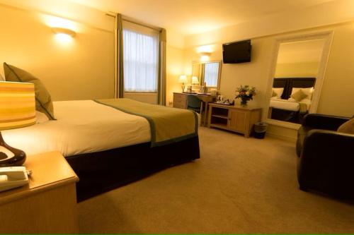 um quarto de hotel com uma cama grande e uma casa de banho em The Limes Hotel em Stratford-upon-Avon