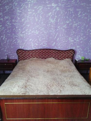a bed in a bedroom with a purple wall at Dava in Gyumri