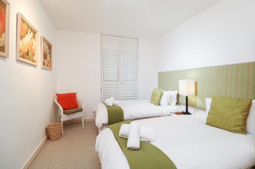 a hotel room with two beds and a chair at 506 Hibernian Towers Luxury Self Catering Apartment Strand Cape Town South Africa in Cape Town