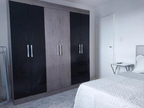 1 dormitorio con armarios negros y 1 cama blanca en Apartamento en Salvador bahía com ar condicionado, en Salvador
