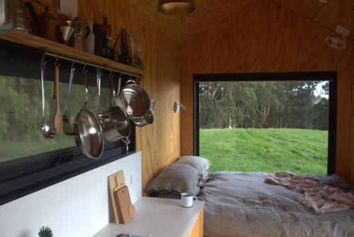 GlenaireにあるThe Perfect Tiny House in Natureのベッドと鍋やフライパンが置かれた窓のある部屋