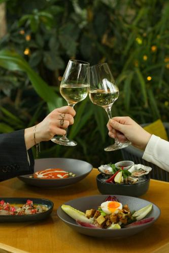 two people are holding glasses of white wine at Hotel Jakarta Amsterdam in Amsterdam