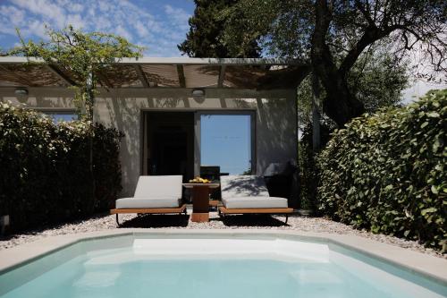 a swimming pool in front of a house with two chairs at Rodostamo Hotel & Spa- Adults Friendly in Kommeno
