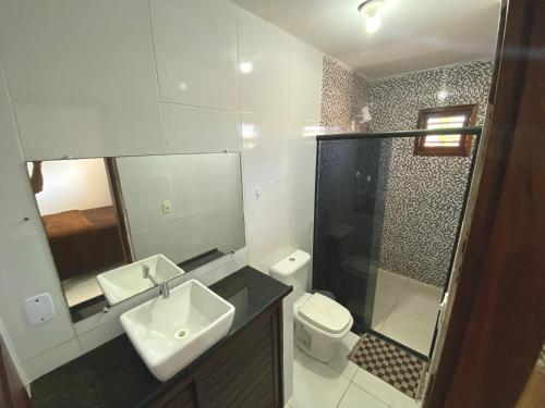 een badkamer met een wastafel, een toilet en een spiegel bij SANNY Pousada e Hostel in Pipa