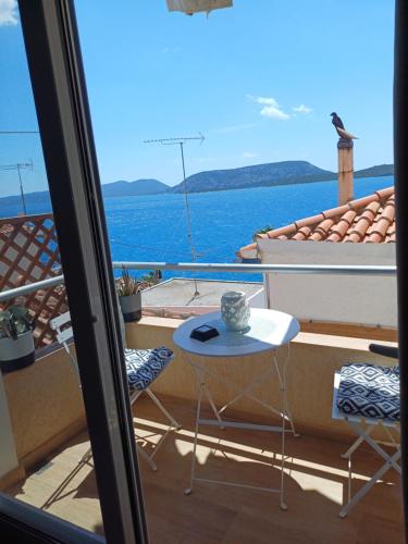 a table and chairs on a balcony with a view of the ocean at Asterias blue Studio in Ermioni