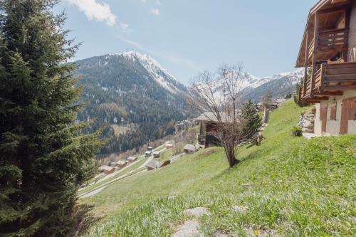 una collina erbosa con una casa e montagne sullo sfondo di Studio avec vue sur les montagnes a Grimentz