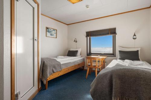 um quarto com duas camas e uma mesa e uma janela em Halne Fjellstugu em Maurset