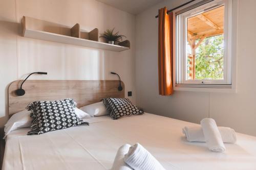 ein Schlafzimmer mit einem großen weißen Bett mit zwei Kissen in der Unterkunft ISOLA VERDE Camping Village in Nettuno