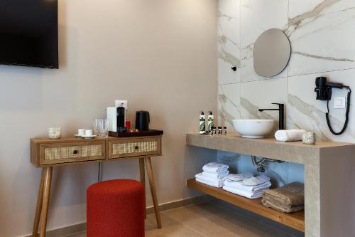 a bathroom with a sink and a table with a red stool at Lotus Rise Hotel - Adults Only in Hersonissos