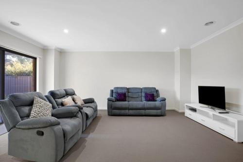 a living room with two couches and a flat screen tv at Modern Pakenham Family Home near Lakeside in Pakenham