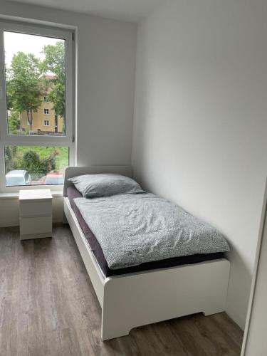 um quarto branco com uma cama e uma janela em Wunderschöne Unterkunft in Leipzig em Taucha