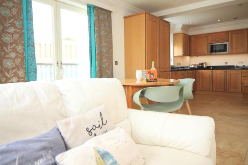 a living room with a white couch and a kitchen at 50m FROM THE BEACH, dogs welcome in St Merryn