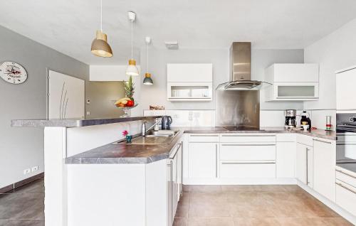 - une cuisine avec des placards blancs et des comptoirs en marbre dans l'établissement Lovely Home In Saint-Georges-De-Didon, à Saint-Georges-de-Didonne