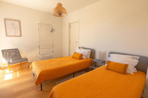 een kamer met 2 bedden en een stoel bij Casas do Forte Sun 4pax by Portugal Hideaway in Cabanas de Tavira