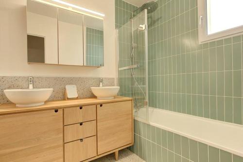 a green tiled bathroom with two sinks and a shower at Villa Les Fleurs in Montigny-le-Bretonneux