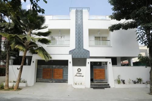 um edifício branco com uma porta e palmeiras em Collection O Prime Residency em Bangalore