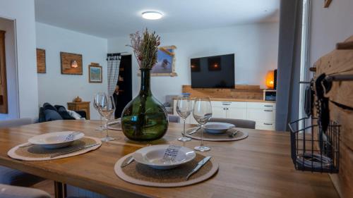 een houten tafel met wijnglazen en een vaas bij Appartement avec Jardin à 10 min d'Annecy in Charvonnex