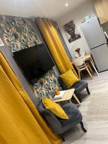 Elle comprend un salon doté de rideaux jaunes et d'une télévision à écran plat. dans l'établissement Chez fati, à Paris