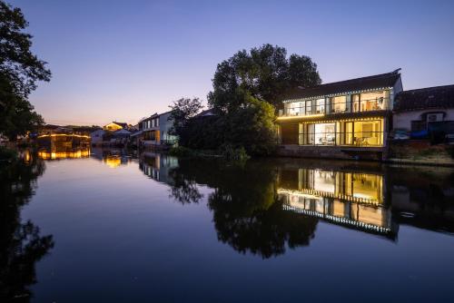 a building next to a river at night at Tongli Slowlife River View Inn in Suzhou