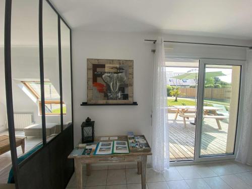 Cette chambre comprend une table et une porte coulissante en verre. dans l'établissement Maison lumineuse près de la plage - Jardin privé, 3 chambres, équipements bébé inclus - FR-1-542-57, à Trégastel