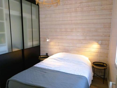 Un dormitorio con una cama con una pared de madera. en Maison lumineuse près de la plage - Jardin privé, 3 chambres, équipements bébé inclus - FR-1-542-57, en Trégastel