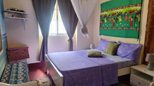 - une chambre avec un lit violet et une fenêtre dans l'établissement Casa de Férias, à Tarrafal