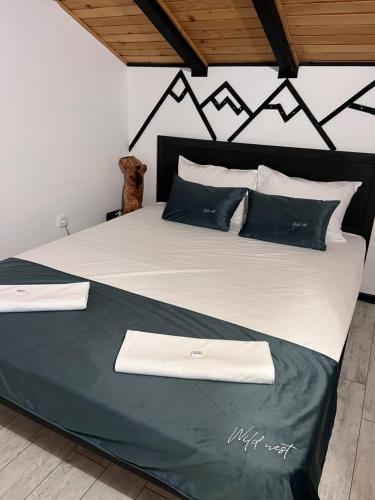 a large bed with black and white sheets and pillows at Wild nest Zlatibor Bear in Zlatibor