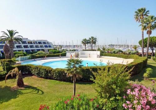 un complexe avec piscine et palmiers dans l'établissement Appartement cosy à Port Camargue, au Grau-du-Roi