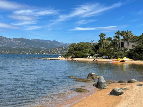 a beach with rocks in the water and mountains at Maranatha Résidence avec plage privée, piscine chauffée in Porto-Vecchio