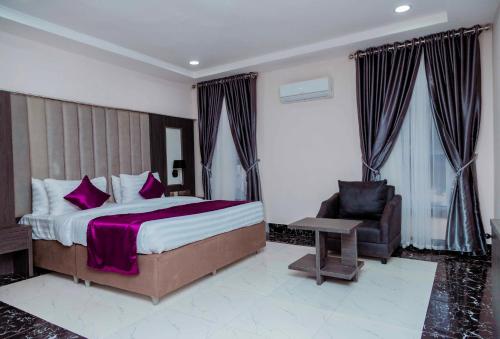 um quarto com uma cama grande e uma cadeira em Fabino by Top Rank Hotels em Abuja
