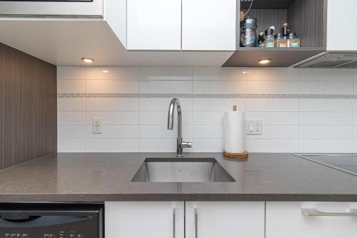 a kitchen with a sink and white cabinets at Sunlit Urban Charm In Old Town Victoria in Victoria