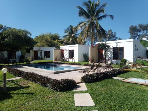 a house with a swimming pool and a palm tree at Telvina Beach Lodge in Vilanculos