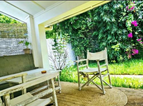 einen Stuhl neben einem Tisch auf einer Veranda in der Unterkunft 2 Bedroom Holiday Cottages Bofa Road, Kilifi in Kilifi
