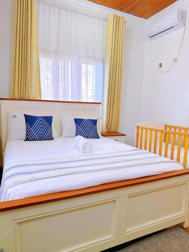 a bedroom with a large white bed with blue pillows at Villa Ella in Mombasa