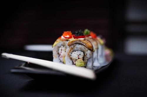 a piece of sushi sitting on a plate with chopsticks at The Alcor Hotel in Jamshedpur