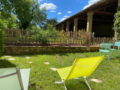 une chaise jaune assise dans l'herbe dans une cour dans l'établissement Mazet au pied des Alpilles, avec Piscine & Pétanque, à Salon-de-Provence