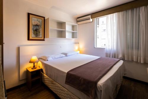 a bedroom with a bed with a lamp and a window at Hotel Golden Star in Curitiba