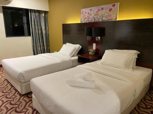 a hotel room with two beds with towels on them at KK Homestay City Deluxe room - Ming Garden Hotel & Residence in Kota Kinabalu