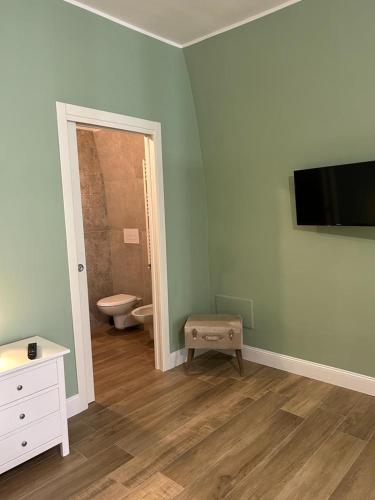 ein Bad mit WC und ein TV an der Wand in der Unterkunft RoMa Apartment & Room in Canosa di Puglia
