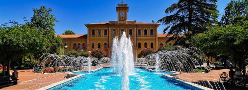 a fountain in front of a building with a clock tower at Hotel Villa Pozzi in Cattolica